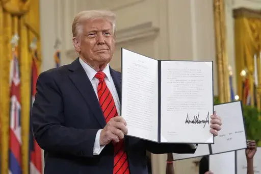 President Donald Trump holds up a signed executive order at an education event in the East Room of the White House in Washington, Thursday, March 20, 2025. (AP Photo/Ben Curtis)