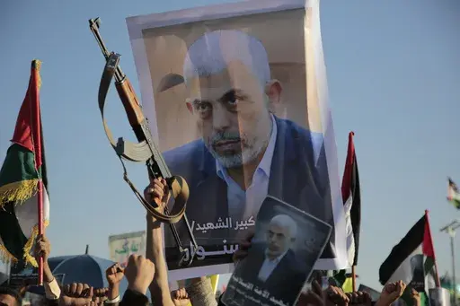 Houthi supporters raise a poster of Hamas leader Yahya Sinwar, who killed by Israeli troops in Gaza, during an anti-Israel rally in Sanaa, Yemen, Friday, Oct. 18, 2024. (AP Photo/Osamah Abdulrahman)