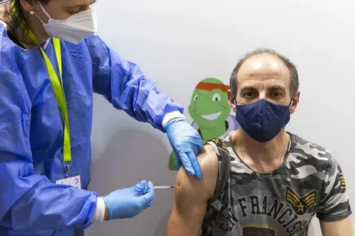 A person gets vaccinated against the COVID-19 virus as the compulsory COVID-19 vaccination starts in Vienna, Austria, Friday, Feb. 4, 2022. (AP Photo/Lisa Leutner)