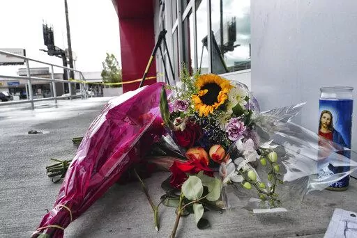 A votive candle and flowers are left for a teen who was fatally shot at a department store in the North Hollywood section of Los Angeles on Saturday, Dec. 25, 2021. The coroner's office has identified the 14-year-old girl who was fatally shot by Los Angeles police the day before, when officers fired on an assault suspect and a bullet went through the wall and struck the girl as she was in a clothing store dressing room. (AP Photo/Richard Vogel)