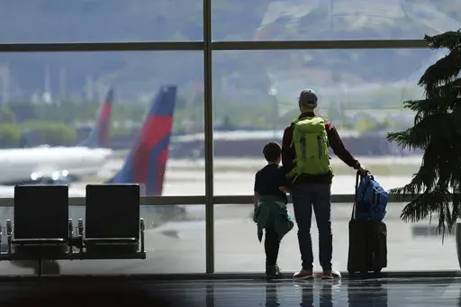 Travelers pass through Salt Lake City International Airport on May 24, 2024, in Salt Lake City. On Thursday, Aug. 1, 2024, Transportation Secretary Pete Buttigieg is expected to announce a new rule that would require airlines to do everything possible to ensure parents can sit with young children on flights. (AP Photo/Rick Bowmer, File)