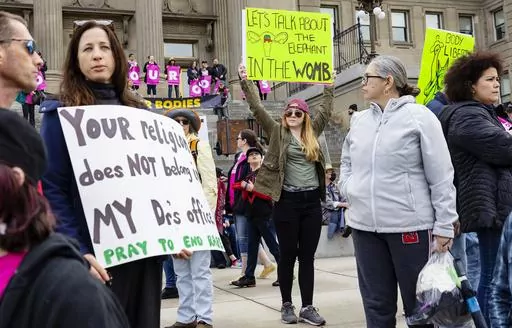 Boise, Idaho, resident Autumn Myers holds a sign with the Republican Party elephant symbol inside the outline of a uterus that reads, "Let's talk about the elephant in the womb," during a Planned Parenthood rally for abortion rights at the Idaho Statehouse in downtown Boise, May 14, 2022. Idaho lawmakers are considering a measure that would bar adults from taking minors to obtain an abortion without their parent's consent. (Sarah A. Miller/Idaho Statesman via AP, File)