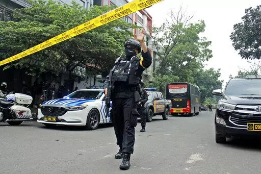 A police officer gestures at the crowd to move back as he guards a road leading to a police station where a bomb exploded in Bandung, West Java, Indonesia, Wednesday, Dec. 7, 2022. A man blew himself up Wednesday at a police station on Indonesia's main island of Java in what appeared to be the latest in a string of suicide attacks in the world's most populous Muslim nation. (AP Photo/Kholid Parmawinata)