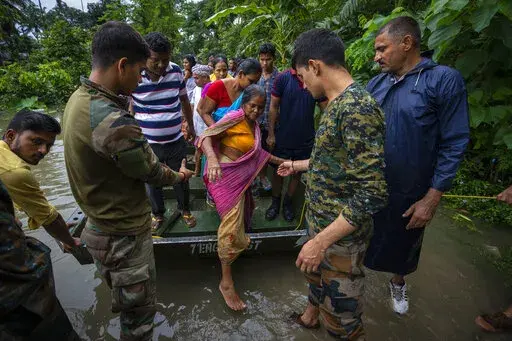 Indian army personnel rescue flood-affected villagers on a boat in Jalimura village, west of Gauhati, India, Saturday, June 18, 2022. More than a dozen people have died as massive floods ravaged northeastern India and Bangladesh, leaving millions of homes underwater and severing transport links, authorities said Saturday. (AP Photo/Anupam Nath)