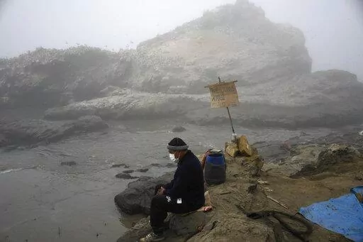 Fisherman Walter de la Cruz sits on the shore of the oil-stained Cavero Beach, unable to fish after a spill in the Ventanilla district of Callao, Peru, Jan. 21, 2022. De la Cruz, 60, is one of more than 2,500 fishermen whose livelihoods have been cast into doubt as a result of a large crude-oil spill by the Spanish-owned Repsol oil refinery on Jan. 15. (AP Photo/Martin Mejia, File)