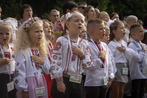 Schoolgirls sing Ukraine's national anthem as they attend a ceremony of the first day in school in Bucha, Ukraine, Friday, Sept. 1, 2023. Ukraine marks Sept. 1 as Knowledge Day, as a traditional launch of the academic year. (AP Photo/Efrem Lukatsky)