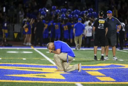 Bremerton High School assistant coach Joe Kennedy takes a knee and prays at the 50-yard line after Bremerton's win over Mount Douglas in a high school football game at Bremerton Memorial Stadium in Bremerton, Wash., on Sept. 1, 2023. Kennedy, the praying football coach who had a long legal battle to get his job back, resigned Wednesday, Sept. 6, 2023, after his first game back on the job. He cited multiple reasons for his resignation including taking care of an ailing family member out of state.
