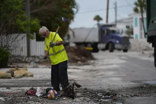Teams work to clean up piles of debris from Hurricane Helene flooding ahead of the arrival of Hurricane Milton, in Holmes Beach on Anna Maria Island, Fla., Tuesday, Oct. 8, 2024. (AP Photo/Rebecca Blackwell)