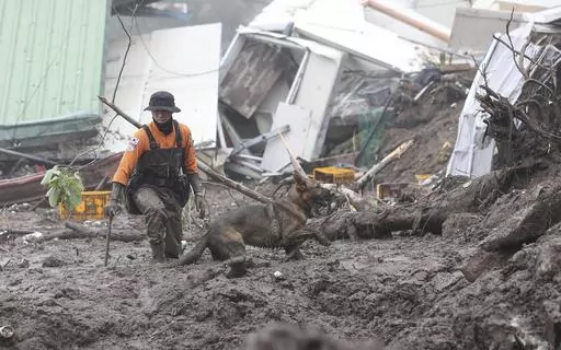 A rescue worker with a dog searches for people at the site of a landslide caused by heavy rain in Yecheon, South Korea, July 16, 2023. Scientists say increasingly frequent and intense storms could unleash more rainfall in the future as the atmosphere warms and holds more moisture. (Yun Kwan-shick/Yonhap via AP, File)