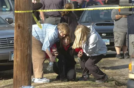People are comforted near Sandy Hook Elementary School, Dec. 14, 2012 in Newtown, Conn. Conspiracy theorist Alex Jones is seeking court permission to convert his personal bankruptcy reorganization to a liquidation, which would lead to a sell-off of a large portion of his assets to help pay some of the $1.5 billion he owes relatives of victims of the Sandy Hook Elementary School shooting. (AP Photo/Hearst Connecticut Media, Alex von Kleydorff via AP, File)