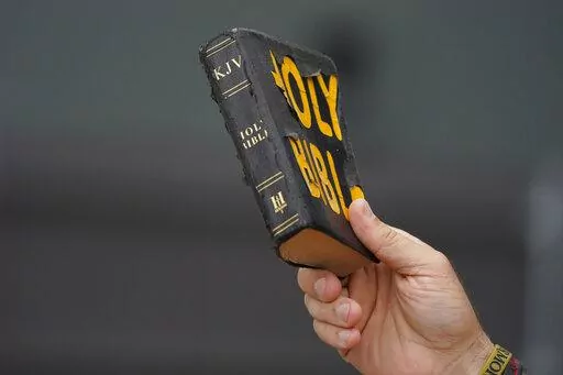 Bryan Peden, an anti-abortion supporter stands outside the Jackson Women's Health Organization clinic in Jackson, Miss., and waves his King James version of the Bible, as he cries out to women entering the medical facility to not have and abortion, Saturday, July 2, 2022. The clinic is the only facility that performs abortions in the state. (AP Photo/Rogelio V. Solis)