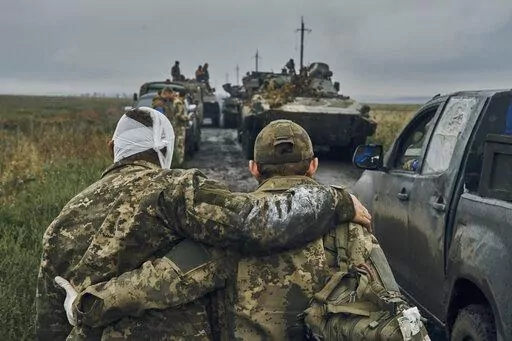 A Ukrainian soldier helps a wounded comrade on the road in reclaimed territory in the Kharkiv region, Ukraine, on Sept. 12, 2022. Some experts say the yearlong conflict that already has killed tens of thousands and reduced whole cities to smoldering ruins could drag on for many more years. (AP Photo/Kostiantyn Liberov, File)