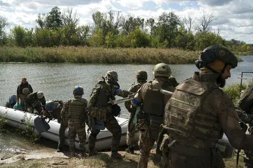 Ukrainian servicemen from Dnipro-1 regiment unload a boat in the retaken village of Shchurove, Ukraine, Sunday, Sept. 25, 2022. (AP Photo/Leo Correa)