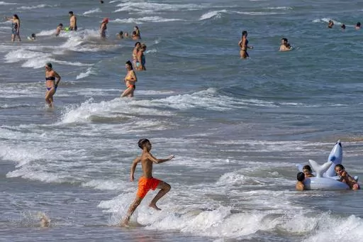 People cool off on Puerto de Sagunto beach in Spain, Tuesday, Aug. 16, 2022. Summer is often a time of having fun, going on vacation and being carefree. But with inflation, layoffs and a looming recession, you may be questioning the financial impact of your summer plans or they suddenly have become out of reach. (AP Photo/Alberto Saiz, File)