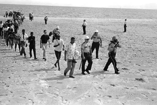 In this June 23, 1963, file photo, Black and white demonstrators, under arrest, walk off the beach at Biloxi, Miss., after staging a wade-in to try to desegregate the Gulf Coast beach. The group was led by Dr. Gilbert Mason, center foreground, and white minister the Rev. R.G. Gallagher, third in line with shorts. On Feb. 20, 2022, people gathered to dedicate a Mississippi historical marker with information about wade-ins that took place in Biloxi 1959, 1960 and 1963. The new marker is a replacem