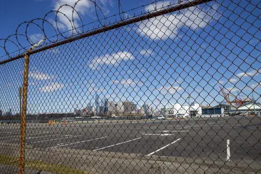 The Manhattan skyline is seen behind the parking lot and terminal of the Brooklyn Cruise Terminal on April 2, 2020, in New York. New York City is temporarily turning the Brooklyn Cruise Terminal into a shelter and services hub for asylum-seekers, Mayor Eric Adams said Saturday, Jan. 21, 2023, announcing the latest in a series of facilities the city has set up, and sometimes shut down, as it strains to handle an ongoing influx. (AP Photo/Mary Altaffer, File)