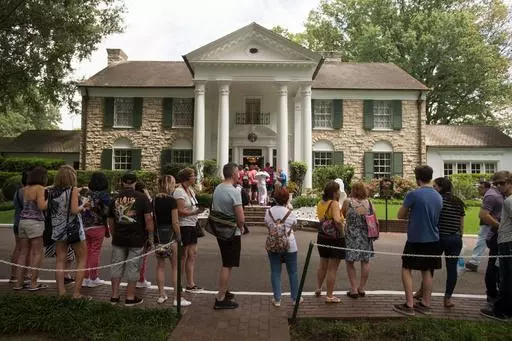 Fans wait in line outside Graceland, Elvis Presley's Memphis home, in Memphis, Tenn., Aug. 15, 2017. A mysterious company has caused a stir for trying to auction Elvis Presley's Graceland in a foreclosure sale this week. A judge has blocked the sale after Presley's granddaughter filed a lawsuit alleging fraud. (AP Photo/Brandon Dill, File)