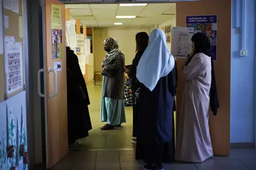 Women wait in line before voting for the first round of the presidential election at a polling station Sunday, April 10, 2022 in the Malpasse northern district of Marseille, southern France. French voters head to polls on Sunday in a runoff vote between centrist incumbent Emmanuel Macron and nationalist rival Marine Le Pen, wrapping up a campaign that experts have seen as unusually dominated by discriminatory discourse and proposals targeting immigration and Islam. (AP Photo/Daniel Cole, File)