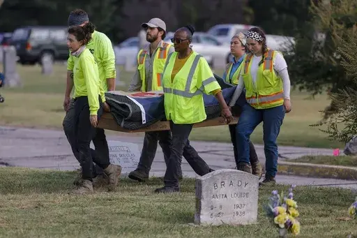 Researchers and burial oversight committee member Brenda Alford carry the first set of remains exhumed from the latest dig site in Oaklawn Cemetery to an onsite lab for further examination, Sept. 13, 2023, in Tulsa, Okla. A third set of remains with a gunshot wound has been found in the search for graves of victims of the 1921 Tulsa Race Massacre at a Tulsa cemetery, according to a state official. (Mike Simons/Tulsa World via AP, File)