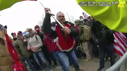 This still frame from Metropolitan Police Department body worn camera video shows Thomas Webster, in red jacket, at a barricade line at on the west front of the U.S. Capitol on Jan. 6, 2021, in Washington. Jurors have returned to court to deliberate in the federal trial of a New York Police Department veteran charged with assaulting an officer who tried to protect the Capitol from an attacking insurrectionist mob last year. Retired NYPD officer Thomas Webster is the first Capitol riot defendant 