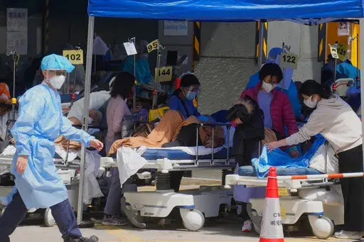 Patients in hospital beds wait at temporary holding area outside Caritas Medical Centre in Hong Kong on Feb. 28, 2022. The fast-spreading omicron variant is overwhelming Hong Kong, prompting mass testing, quarantines, supermarket panic-buying and a shortage of hospital beds. Even the morgues are overflowing, forcing authorities to store bodies in refrigerated shipping containers. (AP Photo/Vincent Yu, File)