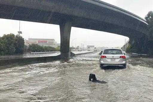 Traffic drives through flooded lanes on Highway 101 in South San Francisco, Calif., Saturday, Dec. 31, 2022. A flood watch is in effect across much of Northern California through New Year's Eve. Officials warned that rivers and streams could overflow and urged residents to get sandbags ready. (AP Photo/Jeff Chiu)