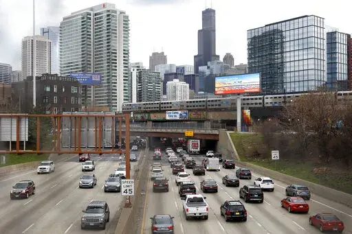 Traffic flows along Interstate 90 highway as a Metra suburban commuter train moves along an elevated track in Chicago on March 31, 2021.   With upcoming data showing traffic deaths soaring, the Biden administration is steering $5 billion in federal aid to cities and localities to address the growing crisis by slowing down cars, carving out bike paths and wider sidewalks, and nudging commuters to public transit.  (AP Photo/Shafkat Anowar, File)