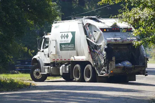 A Richard's Disposal rear loading trash truck rolls through a downtown Jackson, Miss., neighborhood on Friday, Oct. 7, 2022. Mayor Chokwe Antar Lumumba and the Jackson City Council have been feuding for several months over the garbage contract for the city of 150,000 residents. (AP Photo/Rogelio V. Solis)