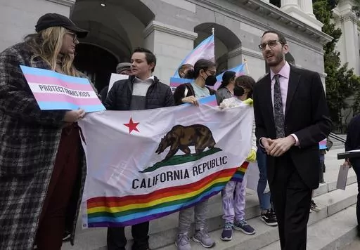 State Sen. Scott Wiener, D-San Francisco, right, prepares to announce his proposed measure to provide legal refuge to displaced transgender youth and their families during a news conference in Sacramento, Calif., on March 17, 2022. San Francisco is repealing a ban on city-funded travel to 30 states that it says restrict abortion, voting and LGBTQ rights after determining the boycott is doing more harm than good. Wiener, a former supervisor-turned-state senator who authored the original ban, agre