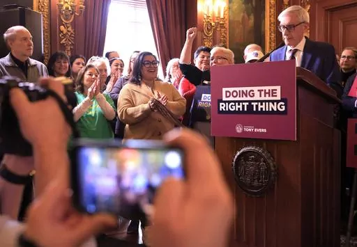 Supporters of Wisconsin Gov. Tony Evers' plan to re-draw the state's legislative maps react as he stands at a podium during the bill-signing event at the Wisconsin State Capitol in Madison, Wis. Monday, Feb. 19, 2024. Democrats tried unsuccessfully for more than a decade to overturn the Republican-drawn maps. But it wasn’t until control of the state Supreme Court flipped in August after the election of liberal Justice Janet Protasiewicz that Democrats found a winning formula. (John Hart/Wiscon