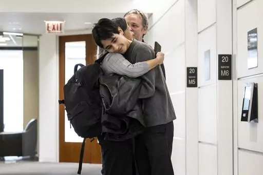 Lucia Morales hugs her 19-year-old son, Rylan Wilder in the hallway at their attorney's office in the Loop, Wednesday, Oct. 18, 2023. Wilder, who was shot and wounded during a 2019 shootout between suburban Chicago police and a bank robbery suspect inside a music school has reached a $1.9 million settlement with the city of Des Plaines. (Ashlee Rezin /Chicago Sun-Times via AP)