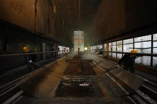 Men work in a galvanizing plant in Cambiano, northern Italy, Friday, Sept. 16, 2022. Zinc baths at Giambarini Group's galvanizing plants in northern Italy must remain super-heated around the clock, seven days a week, an energy-intensive process that has grown exponentially more costly as gas prices spike. The energy crisis facing Italian industry and households is a top voter concern going into Sunday's parliamentary elections as fears grow that astronomically high bills will shutter some busine