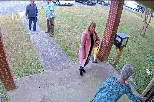 CORRECTS DATE TO JAN. 7, 2021. NOT JAN. 19 In this Jan. 7, 2021 image taken from Coffee County, Ga., security video, Cathy Latham, bottom, who was the chair of the Coffee County Republican Party at the time, greets a team of computer experts from data solutions company SullivanStrickler at the county elections office in Douglas, Ga. Records show that the team traveled to the rural south Georgia county to copy software and data from elections equipment. The Georgia secretary of state's office has