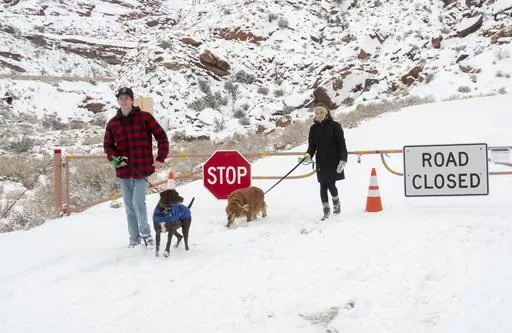 Parker Smith and Hillary Smith hike along a closed road outside Arches National Park in Utah which is closed due to the partial government shutdown, in January 2019. Arizona's Grand Canyon National Park and all five national parks in Utah will remain open if the U.S. government shuts down, Sunday, Oct. 1, 2023. Arizona Gov. Katie Hobbs and Utah Gov. Spencer Cox say that the parks are important destinations and local communities depend on dollars from visitors. (Rick Egan/The Salt Lake Tribune vi