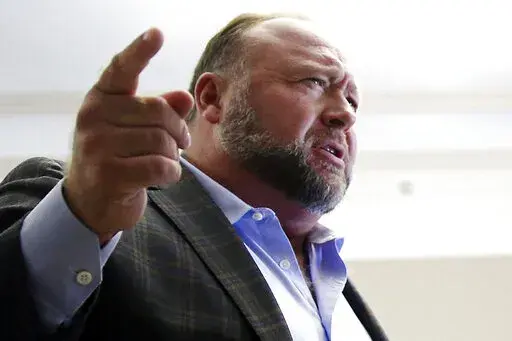 Alex Jones talks to media during a midday break in his trial at the Travis County Courthouse in Austin, Texas, on July 26, 2022. A six-member jury with several alternates in Connecticut will begin hearing evidence, Tuesday, Sept. 13, 2022, on how much Jones should pay the families, since he already has been found liable for damages to them. The trial is expected to last about four weeks. (Briana Sanchez/Austin American-Statesman via AP, Pool)