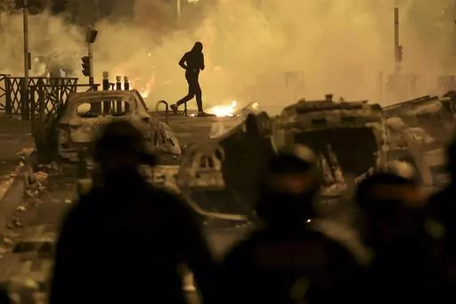 A demonstrator runs on the third night of protests sparked by the fatal police shooting of a 17-year-old driver in the Paris suburb of Nanterre, France, Friday, June 30, 2023. After more than 3,400 arrests and signs that the violence is now abating, France is once again facing a reckoning. (AP Photo/Aurelien Morissard, File)