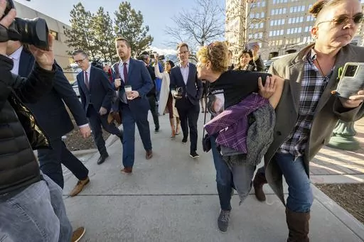 Chrystina Page, right, holds back Heather De Wolf, as she yells at Jon Hallford, left, the owner of Back to Nature Funeral Home, as he leaves with his lawyers following a preliminary hearing, Thursday, Feb. 8, 2024, outside the El Paso County Judicial Building in Colorado Springs, Colo. Hallford and his wife, Carie Hallford, are each charged with 190 counts of abuse of a corpse, five counts of theft, four counts of money laundering and over 50 counts of forgery. De Wolf and Page are mothers of s