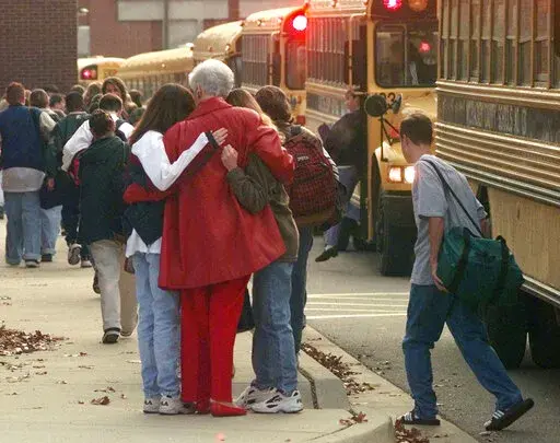 Students arriving at Heath High School in West Paducah, Ky., embrace an unidentified adult on Tuesday, Dec. 2, 1997, after student Michael Carneal opened fire at the school the day before, leaving three students dead and five wounded. In the quarter century that has passed, school shootings have become a depressingly regular occurrence in the U.S. Carneal's upcoming parole hearing in September 2022, raises questions about the appropriate punishment for children who commit heinous crimes. Even if