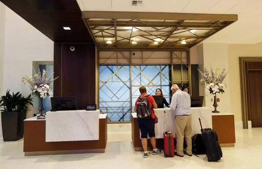FILE- In this Sept. 5, 2018, file photo guests stand at the front desk at the Embassy Suites by Hilton hotel in Seattle's Pioneer Square neighborhood in Seattle. In the 1990s and early 2000s, hotels began offering 100% Satisfaction Guarantees to customers. The promise ensured that customers who were dissatisfied with their service would be guaranteed full refunds with no questions asked. Fast forward to 2022, and it looks like this prevailing expectation has had a negative impact on the overall 