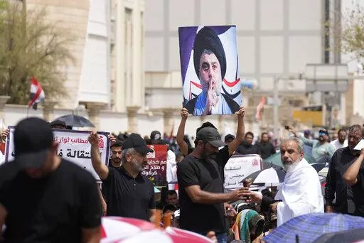 Supporters of Shiite cleric Muqtada al-Sadr with his poster gather during an open-air Friday prayers near the parliament building in Baghdad, Iraq, Friday, Aug. 26, 2022. Al-Sadr's supporters continue their sit-in outside the parliament to demand early elections. (AP Photo/Hadi Mizban)