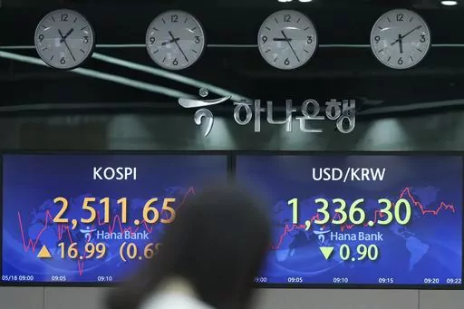 A currency trader walks by the screens showing the Korea Composite Stock Price Index (KOSPI), left, and the foreign exchange rate between U.S. dollar and South Korean won at a foreign exchange dealing room in Seoul, South Korea, Thursday, May 18, 2023. Asian stock markets followed Wall Street higher on Thursday on hopes U.S. political leaders can reach agreement to avoid a potentially disastrous default on government debt. (AP Photo/Lee Jin-man)