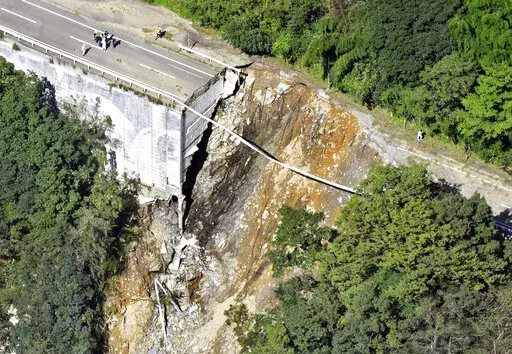 A collapsed road is seen following a typhoon in Morotsuka, Miyazaki prefecture, Tuesday, Sept. 20, 2022. A tropical storm that dumped heavy rain as it cut across Japan moved into the Pacific Ocean on Tuesday after killing a few and injuring more than 100, paralyzing traffic and leaving thousands of homes without power.(Kyodo News via AP)