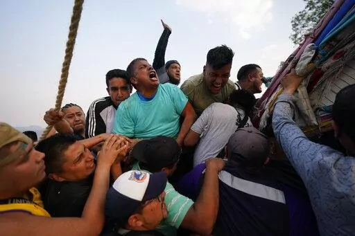 People work to lower a heavy, wooden cross from a hilltop to carry it to a church as part of celebrations marking the day of the Holy Cross, in the Santa Cruz Xochitpec neighborhood of Mexico City, late Monday, May 2, 2022. The importance of the fabric-draped cross is reflected in the town's very name, which means "Holy Cross of the Flowered Hill." (AP Photo/Eduardo Verdugo)