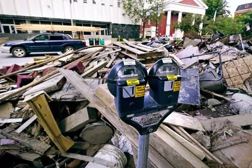 Flooding debris is stacked along State Street, near the state capital building, as a vehicle drives past with a load of lumber tied to the roof in downtown, Tuesday, Aug. 1, 2023, in Montpelier, Vt. The mostly gutted shops, restaurants and businesses that lend downtown Montpelier its charm are considering where and how to rebuild in an era when extreme weather is occurring more often. Vermont's flooding was just one of several major flood events around the globe this summer that scientists have 