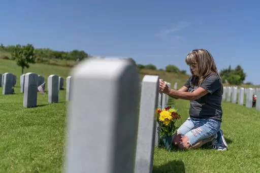 Barbie Rohde touches the tombstone of her son, Army Sgt. Cody Bowman, at the Dallas-Fort Worth National Cemetery, Sunday, June 11, 2023, in Dallas. For decades, discussions of suicide prevention skirted fraught questions about firearms; the Army has punted implementing measures that might be controversial. But a growing consensus movement has taken hold, among researchers, the Veterans Administration, ordinary people like Rohde: if this country wants to get serious about addressing an epidemic o