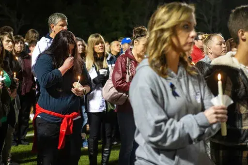 Members of the Bay St. Louis, Miss., community stand with candles during a vigil for Bay St. Louis police Sgt. Steven Robin and Officer Branden Estorffe at Tiger Stadium on Thursday, Dec. 15, 2022. Robin and Estorffe were killed the day before when a woman shot both of them. (Hannah Ruhoff/The Sun Herald via AP)
