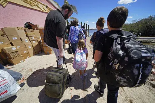 Residents who rode out the storm arrive at a dock to evacuate by boat in the aftermath of Hurricane Ian on Florida's Pine Island, in Lee County, Sunday, Oct. 2, 2022. The only bridge to the island is heavily damaged so it can only be reached by boat or air. The devastation from Hurricane Ian has left schools shuttered indefinitely in parts of Florida, leaving storm-weary families anxious for word on when and how children can get back to classrooms. (AP Photo/Gerald Herbert, File)