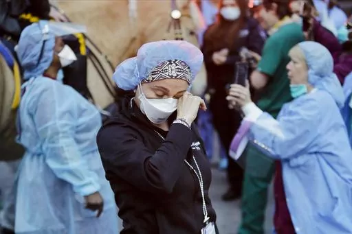 A medical worker reacts as police officers and pedestrians cheer medical workers outside NYU Medical Center in New York, April 16, 2020. Some states that stockpiled millions of masks and other personal protective equipment during the coronavirus pandemic are now throwing the items away. (AP Photo/Frank Franklin II, File)