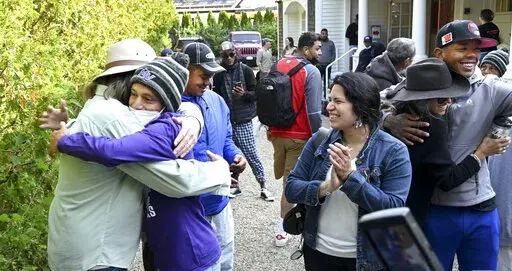 Carlos Munoz reaches out to hug Larkin Stallings of Vineyard Haven, Mass., as the immigrants prepare to leave St. Andrews in Edgartown, Mass., Friday, Sept. 16, 2022. Florida Gov. Ron DeSantis took the playbook of a fellow Republican, Texas Gov. Greg Abbott, to a new level by catching officials flat-footed in Martha's Vineyard, Mass., with two planeloads of Venezuelan migrants. On Friday, the migrants were being moved voluntarily to a military base on nearby Cape Cod, Mass. (Ron Schloerb/Cape Co