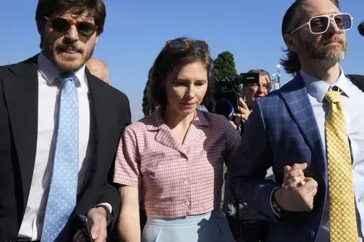 Amanda Knox arrives flanked by her husband Christopher Robinson, right, at the Florence courtroom in Florence, Italy, Wednesday, June 5, 2024. (AP Photo/Antonio Calanni, File)